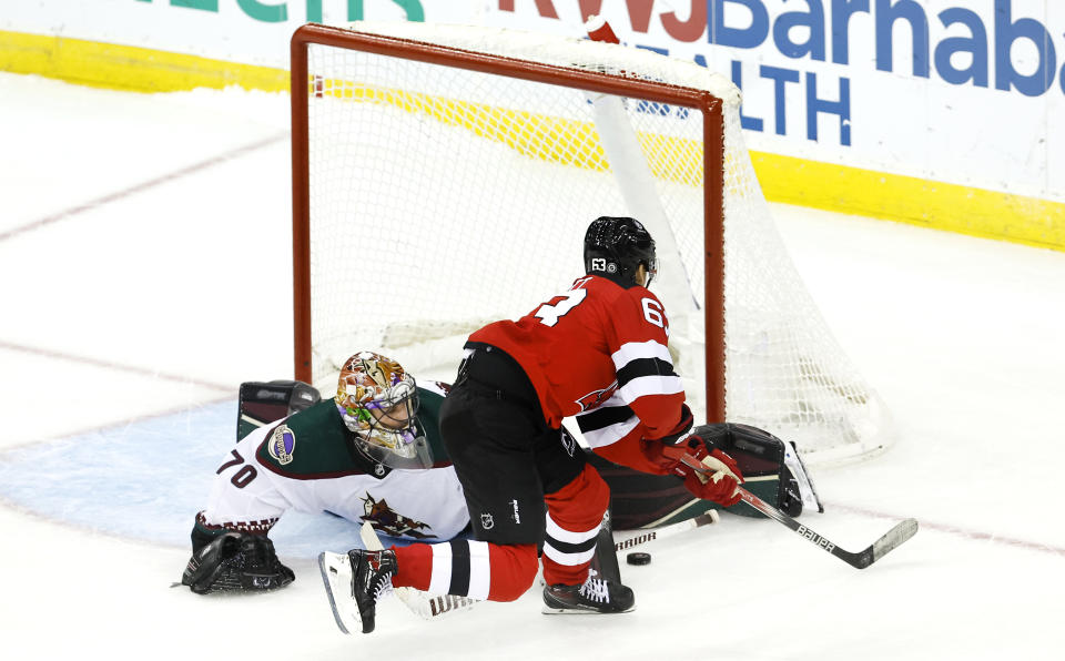 Arizona Coyotes goaltender Karel Vejmelka (70) makes save against New Jersey Devils left wing Jesper Bratt (63) during a shootout of an NHL hockey game Friday, Oct. 13, 2023, in Newark, N.J. (AP Photo/Noah K. Murray)