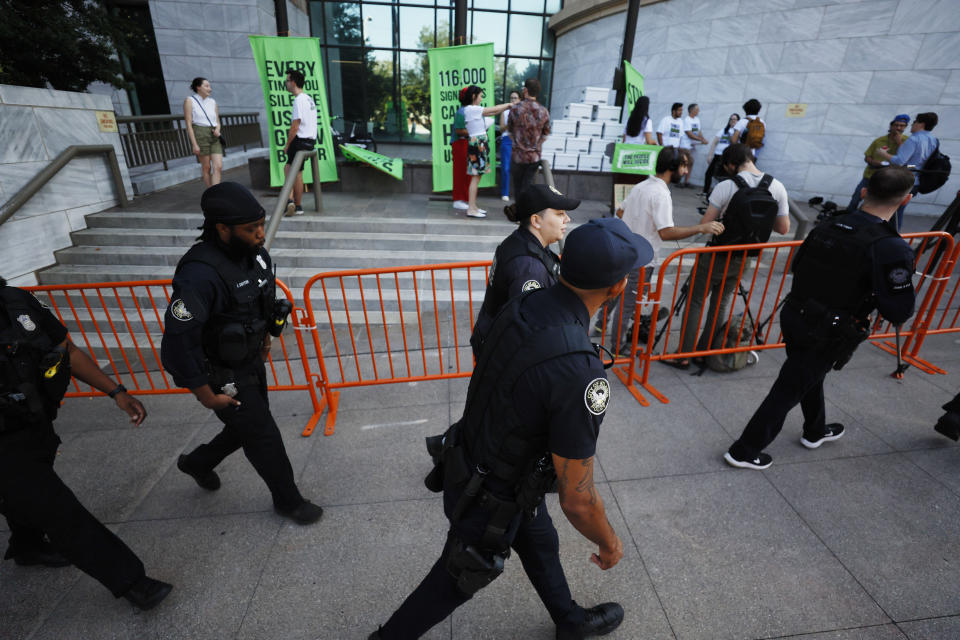 FILE - Atlanta police officers walk in front of the group of activists gathered outside Atlanta City Hall, Monday, Sept. 11, 2023, where they delivered dozens of boxes full of signed petitions to force a referendum on the future of a planned police and firefighter training center. An analysis of petition entries by four news organizations finds it’s unclear whether petitioners have enough valid entries to force the citywide vote, with nearly half the entries unable to be matched to eligible registered Atlanta voters. (Miguel Martinez/Atlanta Journal-Constitution via AP, file) /Atlanta Journal-Constitution via AP)