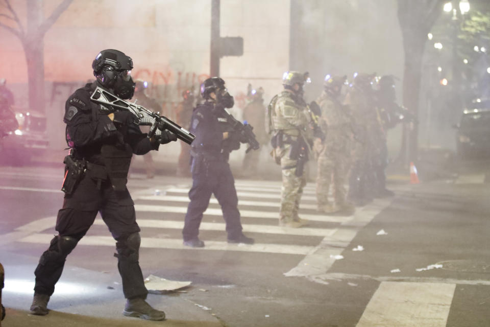 FILE - In this July 28, 2020, file photo, Federal officers deploy tear gas and crowd control munitions at demonstrators during a protest at the Mark O. Hatfield United States Courthouse in Portland, Ore. Federal agents have left Portland, but city officials are still learning about and cleaning tear gas residue that lingers in the streets, dirt and possibly storm drains that empty into the Willamette River. (AP Photo/Marcio Jose Sanchez, File)