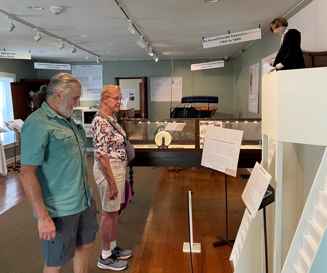 Jon Leuzio and Pat Mahieu read about the Temperance movement in Granville during the nineteenth century at the Granville Historical Museum. The figure at top right is the Rev. Jacob Little, a leader in the drive to halt the sale of liquor in the village.