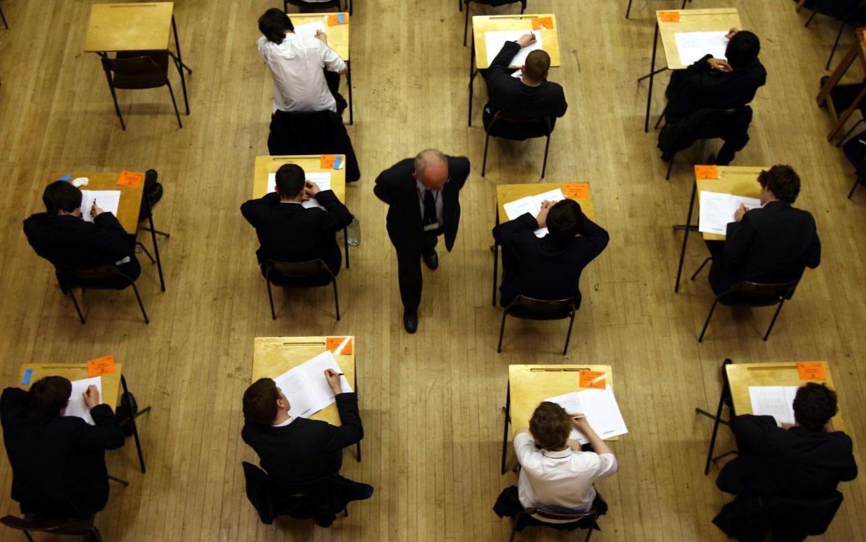 Pupils taking an exam, watched over by an invigilator - David Jones/PA