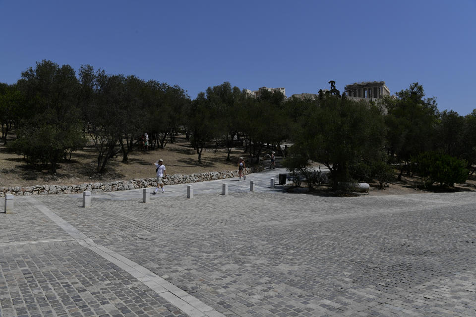 People walk under the ancient Acropolis, in Athens Greece, Tuesday, Aug. 3, 2021. Authorities in Greece have closed the Acropolis and other ancient sites during afternoon hours as a heatwave scorching the eastern Mediterranean continued to worsen. Temperatures reached 42 C (107.6 F) in parts of the Greek capital, as the extreme weather fueled deadly wildfires in Turkey and blazes across the region. (AP Photo/Michael Varaklas)