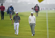 Collin Morikawa, left foreground, talks with Tiger Woods as they walk on the fourth hole of the South Course at Torrey Pines Golf Course during the second round of the Farmers Insurance golf tournament Friday Jan. 24, 2020, in San Diego. (AP Photo/Denis Poroy)