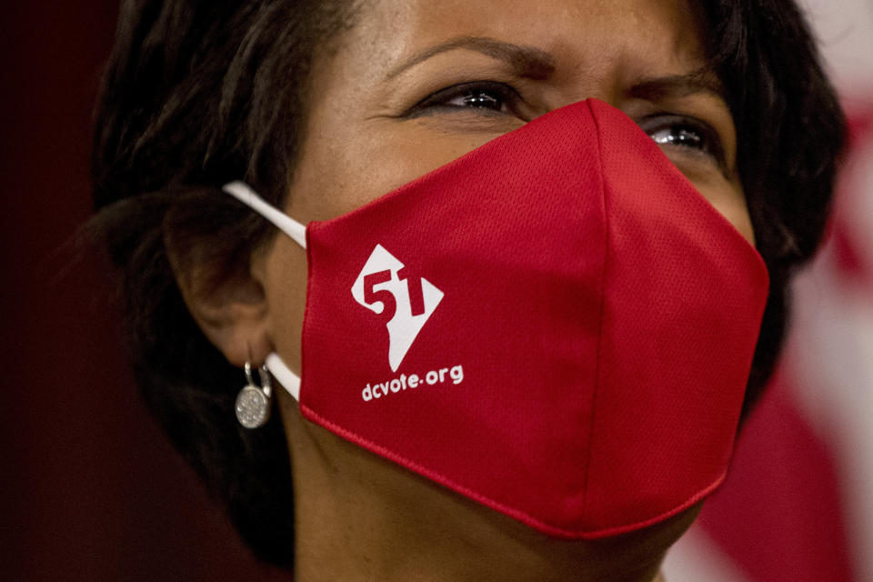 FILE - In this June 16, 2020, file photo District of Columbia Mayor Muriel Bowser wears a mask with the number 51 over a map of the District of Columbia during a news conference on D.C. statehood on Capitol Hill in Washington. Bowser must pull off a public juggling act as the city budget becomes a battleground for the country's debate on overhauling law enforcement. (AP Photo/Andrew Harnik, File)