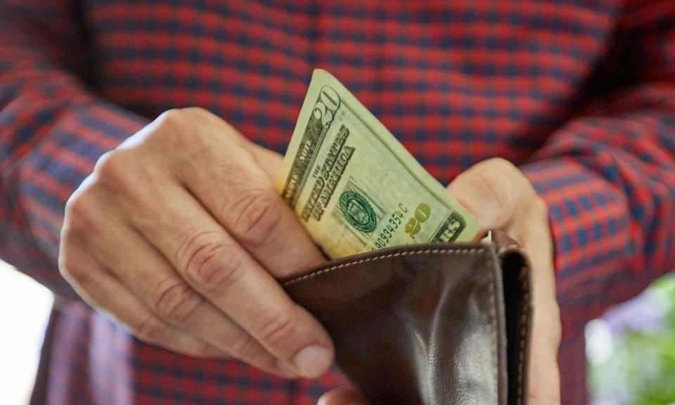 a person pulling out a 20 dollar bill