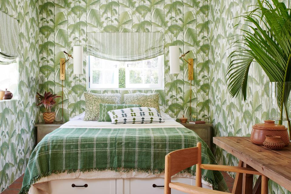 Lee Jofa wall coverings convert the guesthouse into a tropical retreat. The Roman shades are in a Martyn Lawrence Bullard fabric, the sconces are from Circa Lighting, and the desk and chair are from William Laman and Design Within Reach. The Pottery Barn bed anchors a blend of textiles by Martyn Lawrence Bullard, Peter Dunham, Holland & Sherry, and Kerry Joyce.