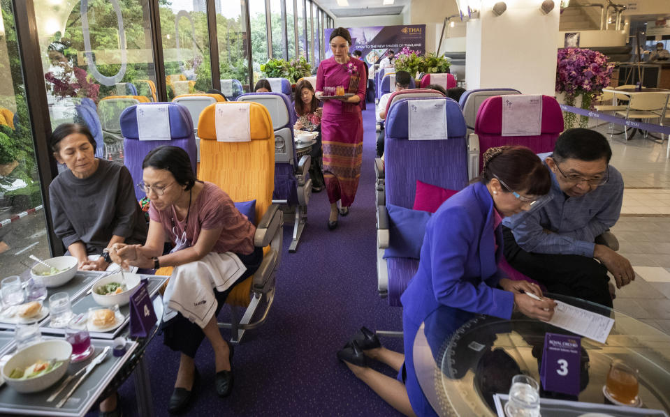 A flight attendant serves welcome drinks in a flight-themed restaurant at the Thai Airways head office in Bangkok, Thailand on Oct. 3, 2020. The airline is selling time on its flight simulators to wannabe pilots while its catering division is serving meals in a flight-themed restaurant complete with airline seats and attentive cabin crew. The airline is trying to boost staff morale, polish its image and bring in a few pennies, even as it juggles preparing to resume international flights while devising a business reorganization plan. (AP Photo/Sakchai Lalit)