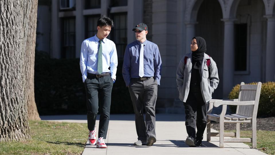 Dr. Seth Holm, chair of modern classics at the Hun School, leads a class of volunteer students that talk with Afghan girls by phone to try and teach them English. Here he speaks with students, two of the original volunteers, Steve F. and Hanan A. at the Hun School in Princeton, NJ on Feb. 14, 2023.