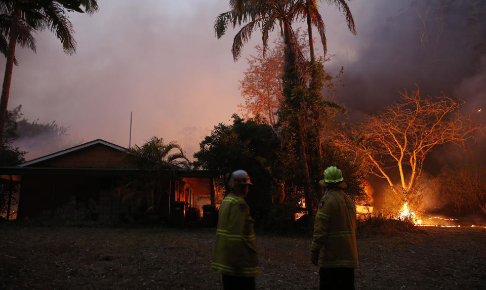 A bushfire in Hillville moves in on a house near the Pacific Highway, north of Nabiac in the Mid North Coast region of NSW, on Tuesday. Source: AAP