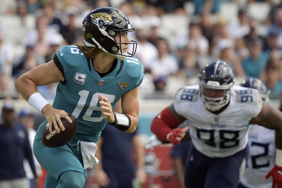 Jacksonville Jaguars quarterback Trevor Lawrence, left, looks for a receiver as Tennessee Titans defensive end Jeffery Simmons (98) rushes during the first half of an NFL football game, Sunday, Oct. 10, 2021, in Jacksonville, Fla. (AP Photo/Phelan M. Ebenhack)