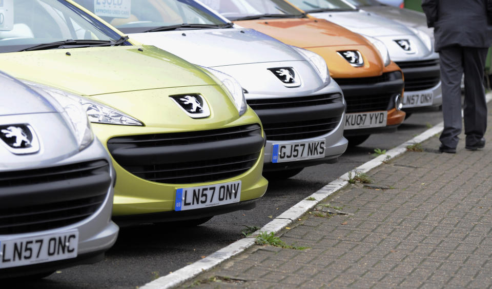 A man passes cars on a showroom forecourt in west London November 6, 2008. British new car registrations fell by an annual 23 percent in October, the steepest decline this year, the Society of Motor Manufacturers and Traders (SMMT) said on Thursday. REUTERS/Toby Melville (BRITAIN)