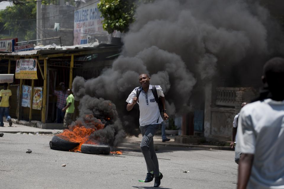 A student runs away from police dispersing a student protest in support of striking teachers as tires burn in Port-au-Prince, Haiti, Wednesday, May 7, 2014. Students are protesting to demand authorities respond to their striking teachers' demands for higher pay and improved working conditions. Students are concerned they will not be able to take exams which allow them to move on to the next level. Public school teachers across Haiti have been on strike for one week. (AP Photo/Dieu Nalio Chery)