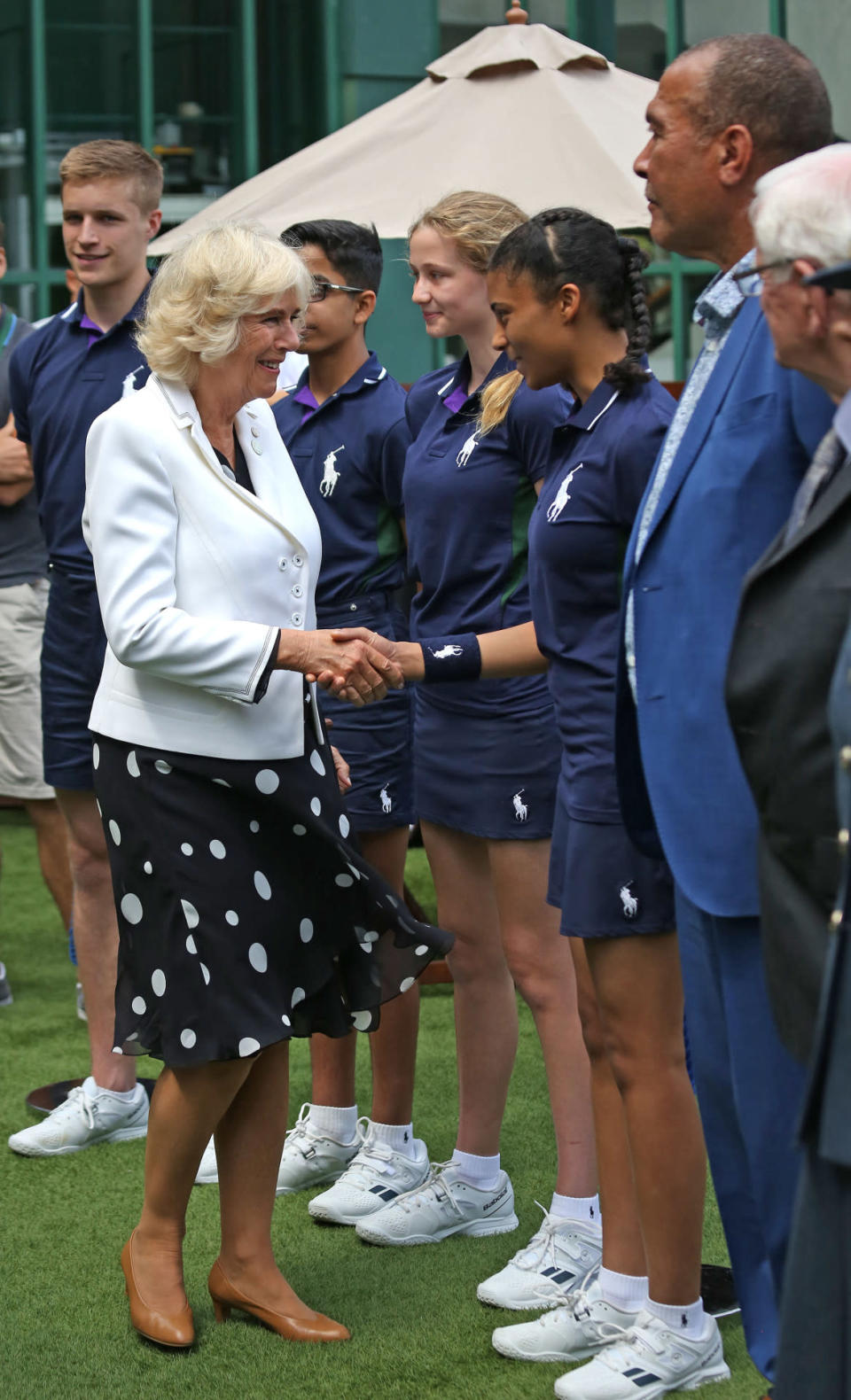 <p>Dressed in a polka dot dress and a tailored jacket, Camilla greeted the ball boys and girls ahead of a Wimbledon match. <i>[Photo: PA Images]</i></p>