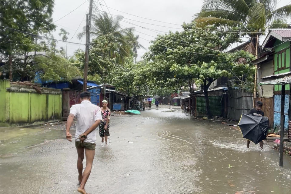 In this image from a video, local people walk on a flooded street caused by heavy rain as Cyclone Mocha approaches in Sittwe, Rakhine State, Myanmar Sunday, May 14, 2023. Bangladesh and Myanmar braced Sunday as the extremely severe cyclone started to hit coastal areas and authorities urged thousands of people in both countries to seek shelter. (AP Photo)