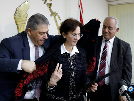 Palestinian Ambassador to Lebanon Ashraf Dabbour (L) helps U.N. Under-Secretary General and ESCWA Executive Secretary Rima Khalaf (C) put on a traditional Palestinian scarf after a news conference announcing her resignation from the United Nations in Beirut, Lebanon, March 17, 2017. REUTERS/Jamal Saidi