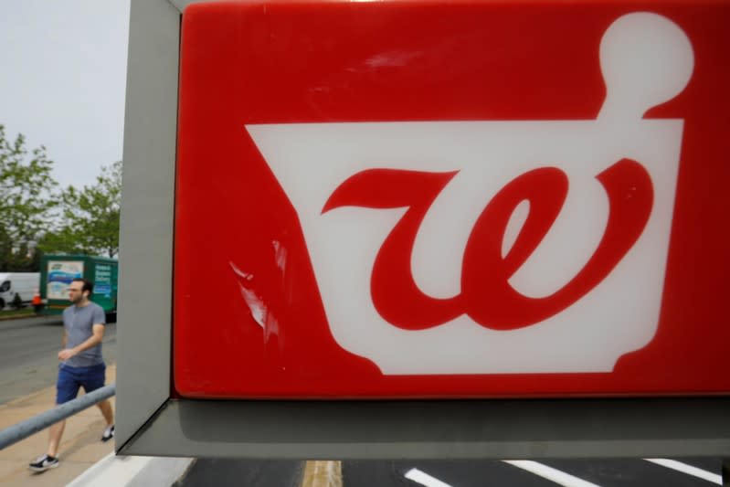 Pedestrian passes a sign for a Walgreens pharmacy in Somerville