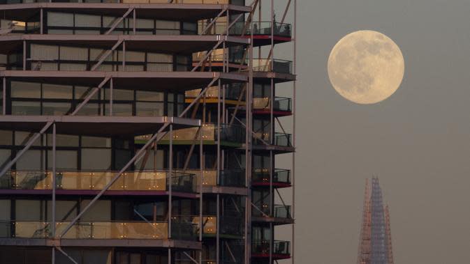 The Wolf Moon, bulan purnama pertama tahun ini, muncul di belakang The Shard di pusat kota London, Senin (17/1/2022). Wolf Moon atau disebut juga Bulan purnama Serigala adalah sebutan untuk bulan purnama pertama di Januari. (Justin TALLIS / AFP)