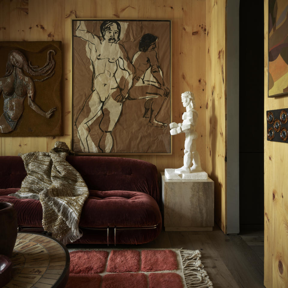 living room with wood panelled walls, red sofa, and white sculpture