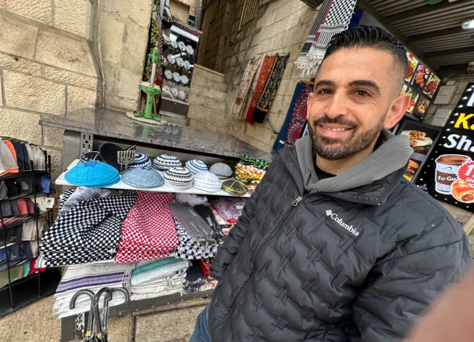 Ahmed at his shop just inside the Jaffa Gate of the Old City of Jerusalem, selling yarmulkes and keffiyehs side-by-side.