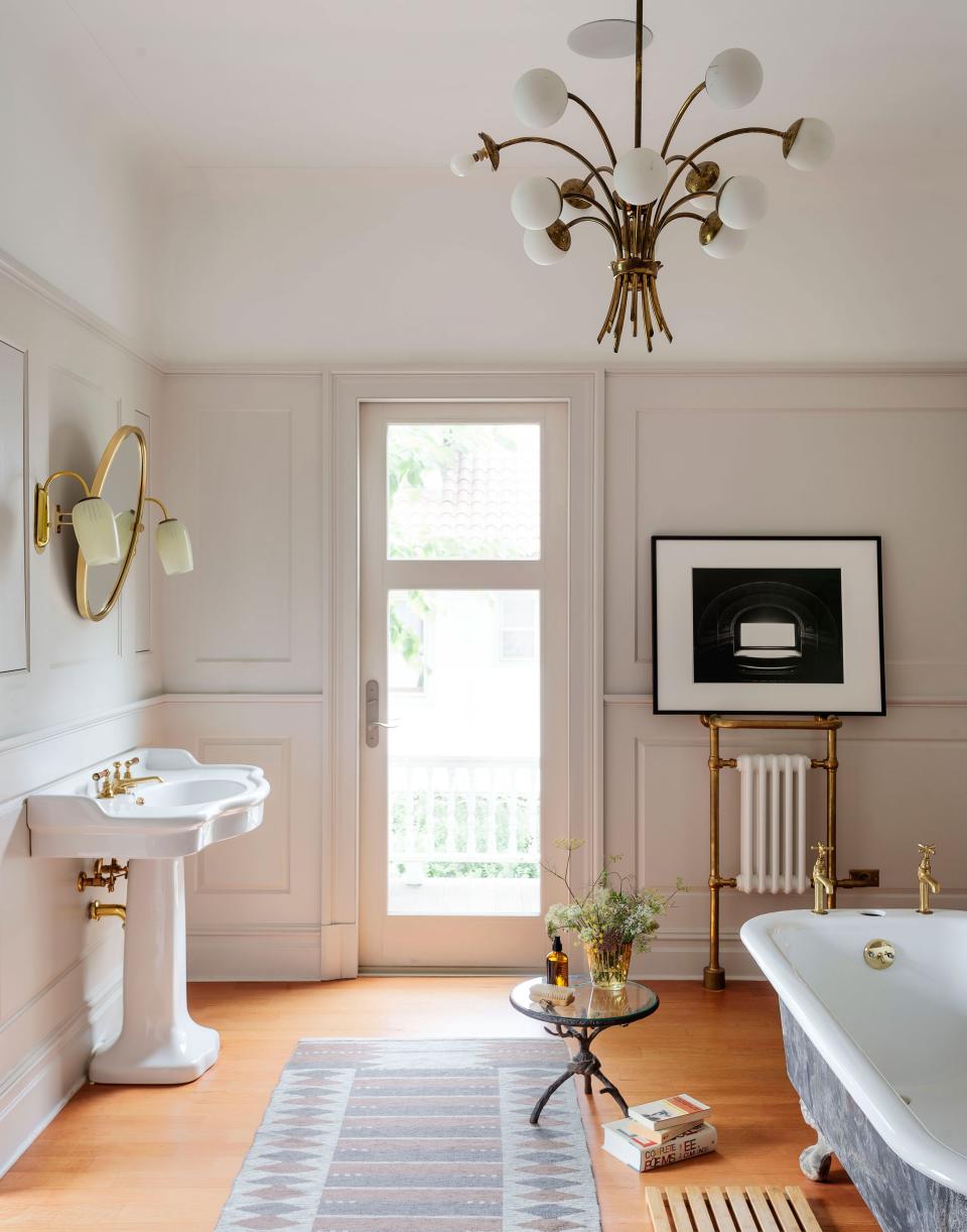 In the newly reconfigured primary bath, a pedestal sink and fixtures by The Water Monopoly mingle with the house’s original tub. Workstead added the historically sensitive paneling.