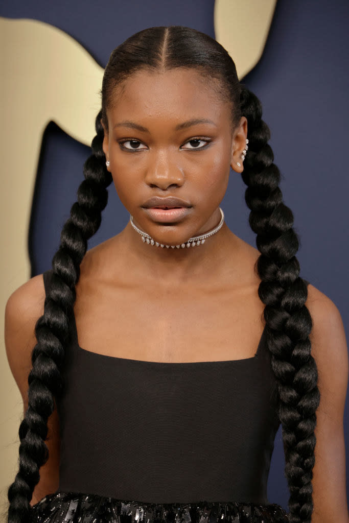 she adorns her look with a silver choker and climber earrings, and her hair is styled in two long braids