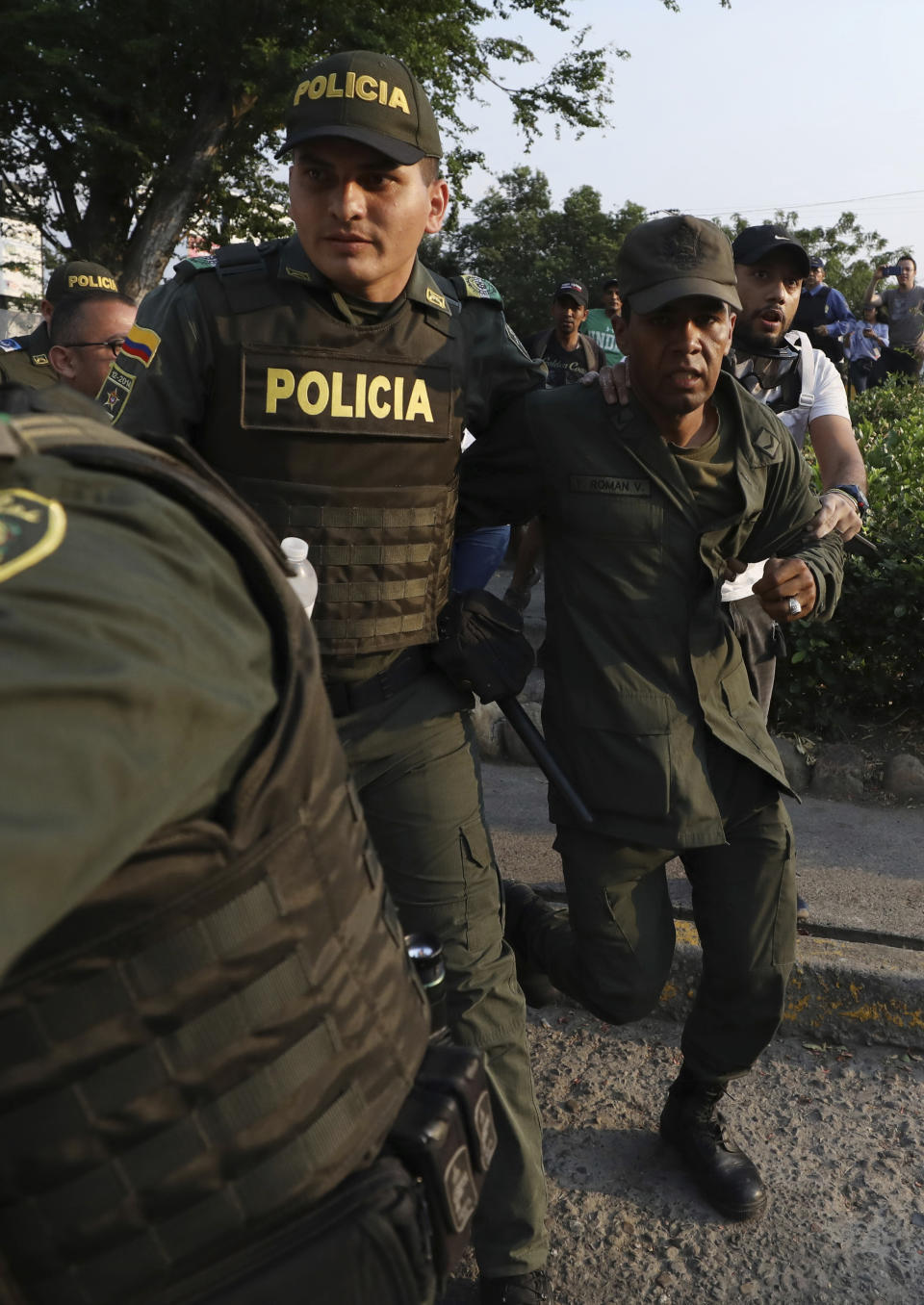 A Venezuelan National Guard, right, deserts his post as Colombian Police escort him after he managed to cross the Simon Bolivar International Bridge where his fellow guardsmen are blocking the entry of U.S.-supplied humanitarian aid, in La Parada, Colombia, Monday, Feb. 25, 2019, on the border with Venezuela. The delivery of humanitarian aid to the economically devastated nation has faltered amid strong resistance from security forces who remain loyal to Venezuelan President Nicolas Maduro. (AP Photo/Fernando Vergara)