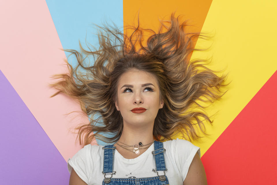 Young woman lying on multicolor Background.Studio Shot