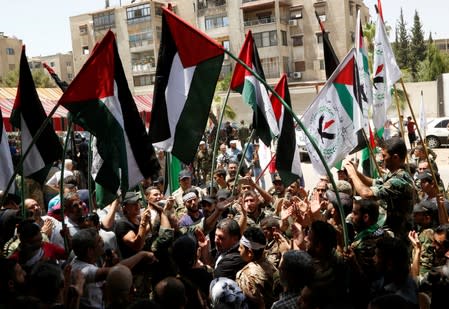 Palestinian refugees hold flags as they take part in a rally at Yarmouk Palestinian camp in Damascus