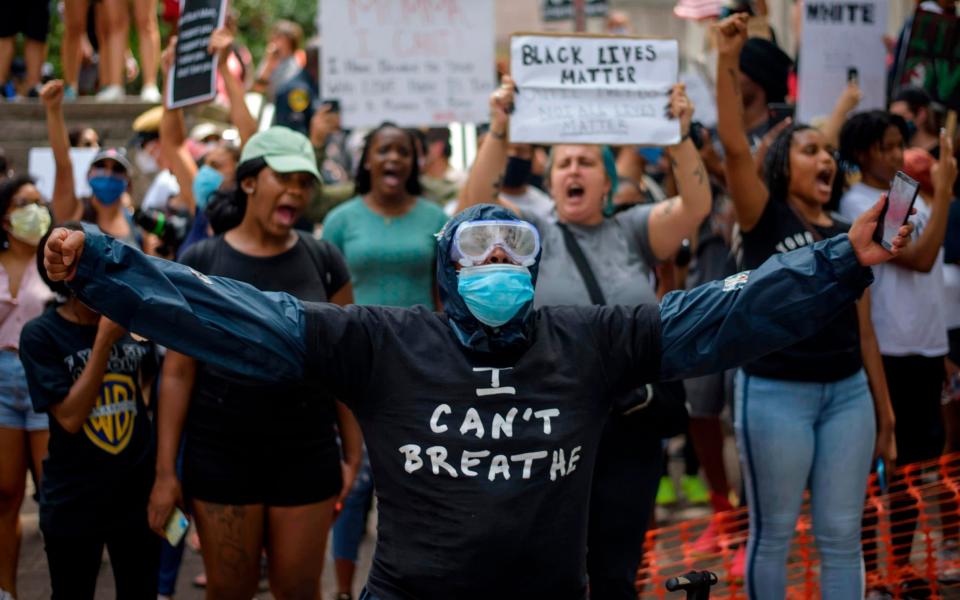 A person wearing facemask and goggles gestures as people gather to protest in Houston - AFP