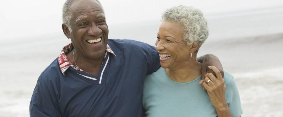 Cheerful African American mature couple with arms around at the beach