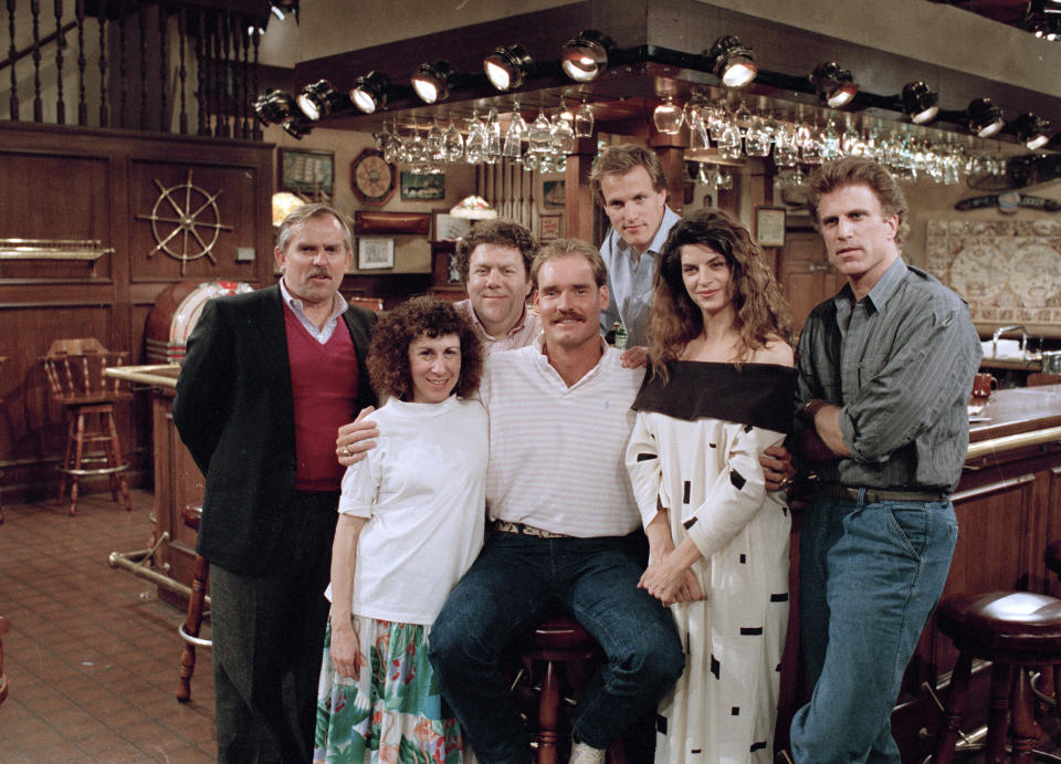 FILE -Boston Red Sox third baseman Wade Boggs, center, poses, March 2, 1988, with the cast of "Cheers" during rehearsal for an episode in which he appears. Cast members include, John Ratzenberger, Rhea Perlman, George Wendt, Woody Harrelson, Kirstie Alley and Ted Danson. Alley, a two-time Emmy winner who starred in the 1980s sitcom “Cheers” and the hit film “Look Who’s Talking,” has died. She was 71. Her death was announced Monday by her children on social media and confirmed by her manager. The post said their mother died of cancer that was recently diagnosed. (AP Photo/Ira Mark Gostin, File)