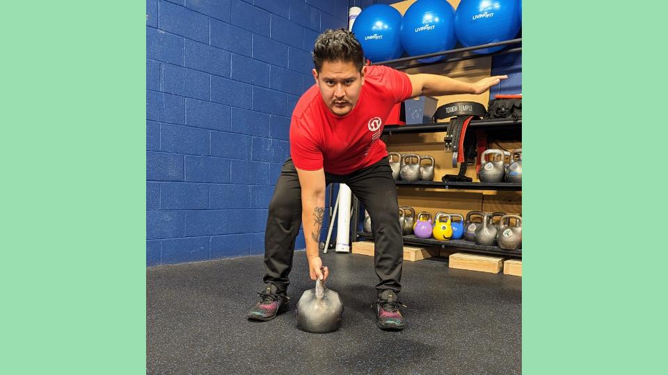 Gio Amatore performing the first phase of the kettlebell drop row with arm straight