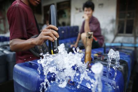 A man fills up his plastic containers with water before setting off to deliver them to residents who increasingly have no access to piped or well water in Pluit, north Jakarta, September 30, 2014. REUTERS/Darren Whiteside