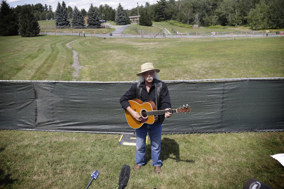 Woodstock veteran Arlo Guthrie plays a song at the original site of the 1969 Woodstock Music and Arts Fair in Bethel, N.Y., Thursday, Aug. 15, 2019. Guthrie is schedule to play a set on the top of hill nearby but told reporters he wanted to play at least one song on the original 1969 site. Woodstock fans are expected to get back to the garden to mark the 50th anniversary of the generation-defining festival. Bethel Woods Center for the Arts is hosting a series of events Thursday through Sunday at the bucolic 1969 concert site, 80 miles (130 kilometers) northwest of New York City. (AP Photo/Seth Wenig)