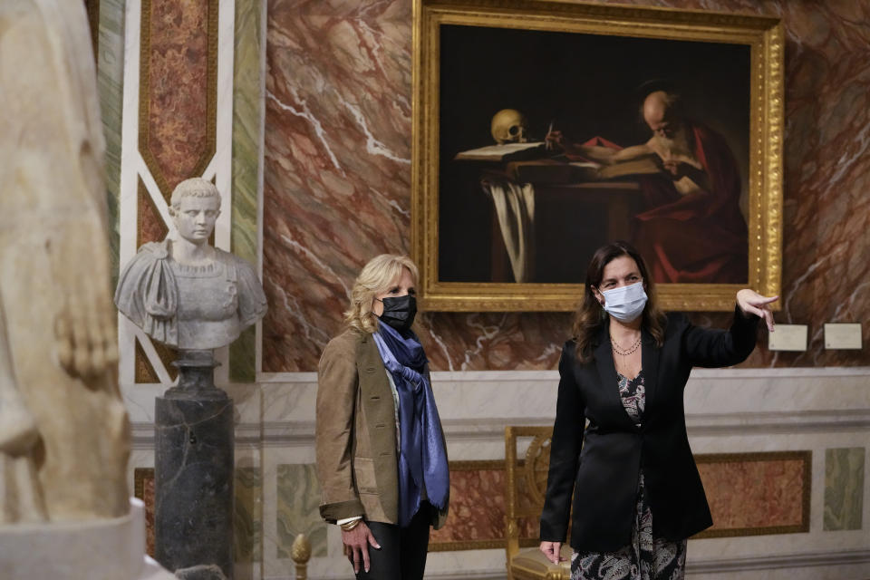 Italian painter Caravaggio's masterpiece titled Saint Jerome Writing is seen in the background as U.S. first lady Jill Biden, left, listens to museum director Francesca Cappelletti, right, during a visit to the Borghese Gallery and Museum on the sidelines of the G20 summit in Rome, Sunday, Oct. 31, 2021. Leaders of the world's biggest economies made a compromise commitment Sunday to reach carbon neutrality "by or around mid-century" as they wrapped up a two-day summit that was laying the groundwork for the U.N. climate conference in Glasgow, Scotland. (AP Photo/Alessandra Tarantino)