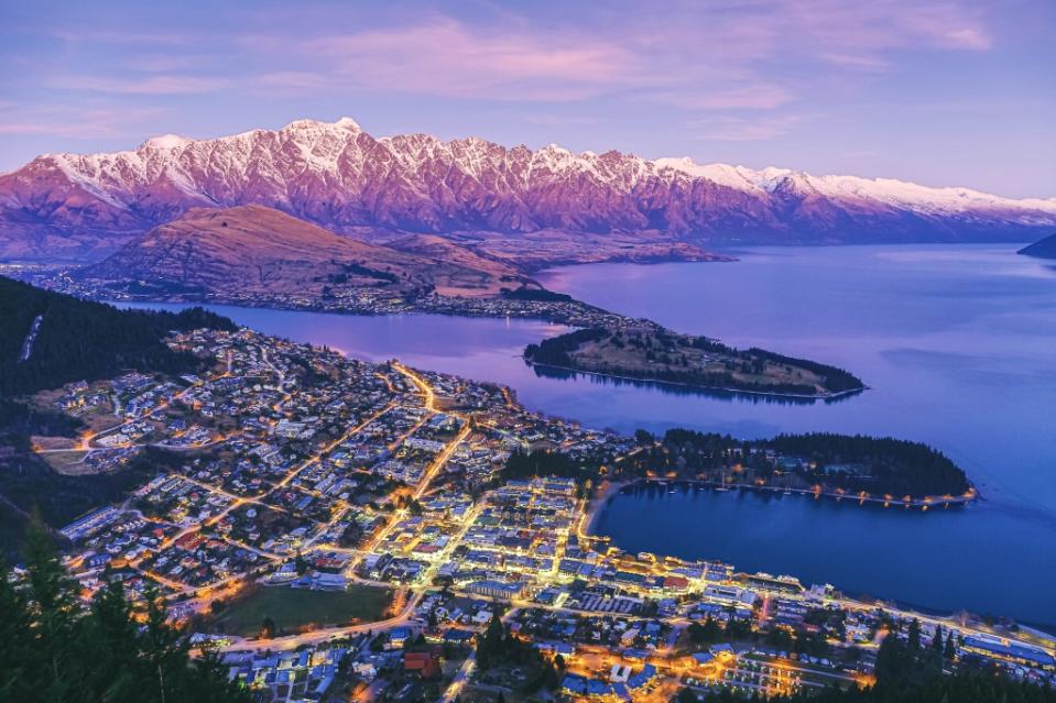 Scenic dusk view of illuminated Queenstown cityscape at beautiful sunset with Lake Wakatipu and The Remarkables mountain range, Queenstown, famous resort town in Otago Region, South Island, New Zealand.