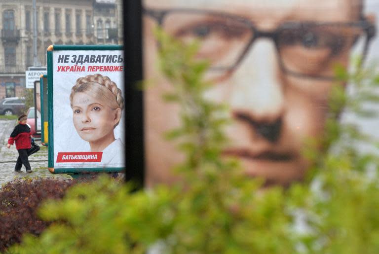 A woman walks in the eastern city of Lviv on October 23, 2014 near an election campaign poster of Yulia Tymoshenko, the leader of the Batkivschyna party, and one of Ukrainian Prime Minister Arseniy Yatsenyuk