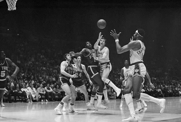 West, right, passes the ball during a game between the Lakers and the Knicks at New York's Madison Square Garden on April 28, 1970. Covering West are the Knicks' Willis Reed (19), left, and Walt Frazier (10), center.