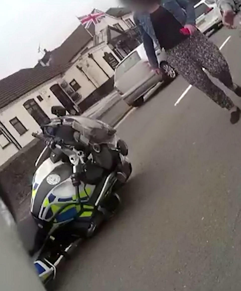 A teenage yob is facing jail after shocking footage caught him ramming a police officer off his motorbike in a stolen car. Callum Fellows, 18, was behind the wheel of a dark blue Seat Leon which was being followed by PC Steve Lovering. When the car stopped at traffic lights the officer drove up to the driver's door but Fellows suddenly reversed before steering straight into PC Lovering's BMW bike. CCTV and the officer’s body-cam captured the shocking moment when PC Lovering was sent sprawling onto Ashes Road in Oldbury, West Mids. The officer is heard shouting out in pain before radioing colleagues for help as Fellows sped away.