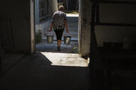 A worker carries buckets of water through the KramAgroSvit dairy farm in Dmytrivka, Donetsk region, eastern Ukraine, Wednesday, Aug. 10, 2022. Rising expenses due to supply chain and logistics disruptions have required large cutbacks in staff and a mass sell-off of livestock, while shellings in the area pose dangers to workers and animals alike. (AP Photo/David Goldman)