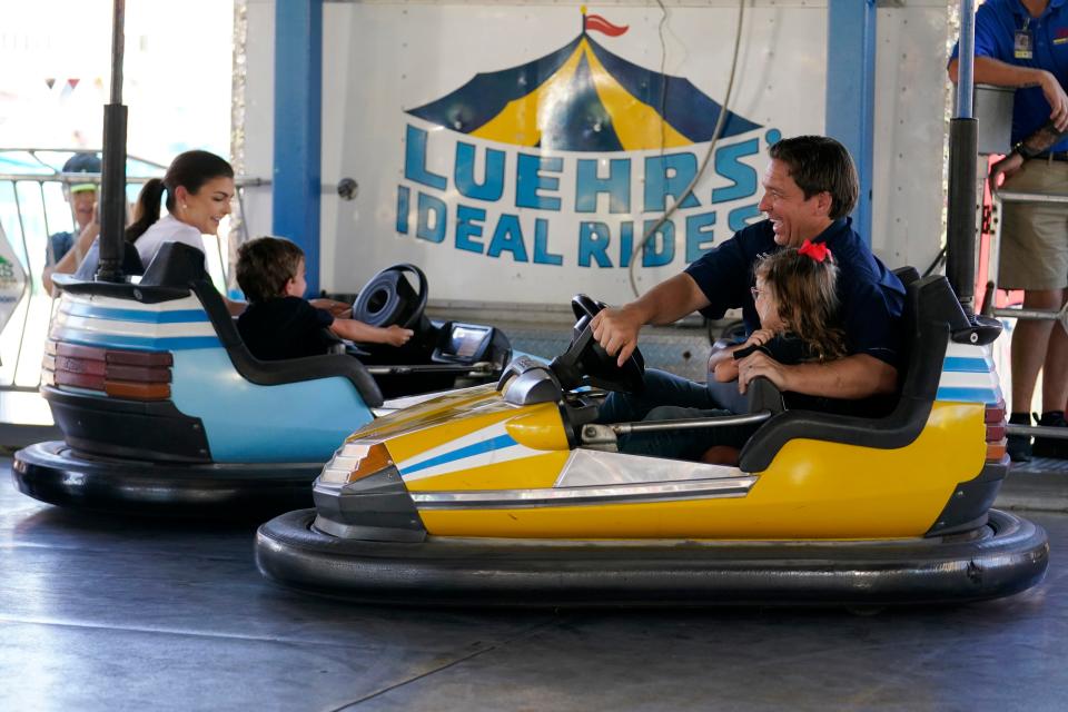 Florida Gov. Ron DeSantis laughs as he drives a bumper car with his daughter as they hit another car driven by his wife, Casey DeSantis, and their son on Aug. 12, 2023, in Des Moines, Iowa, at the state fair.