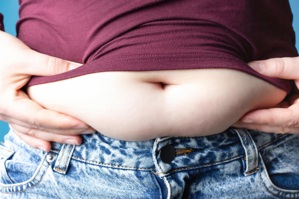 Women's hands hold belly, close-up, the concept of excess weight