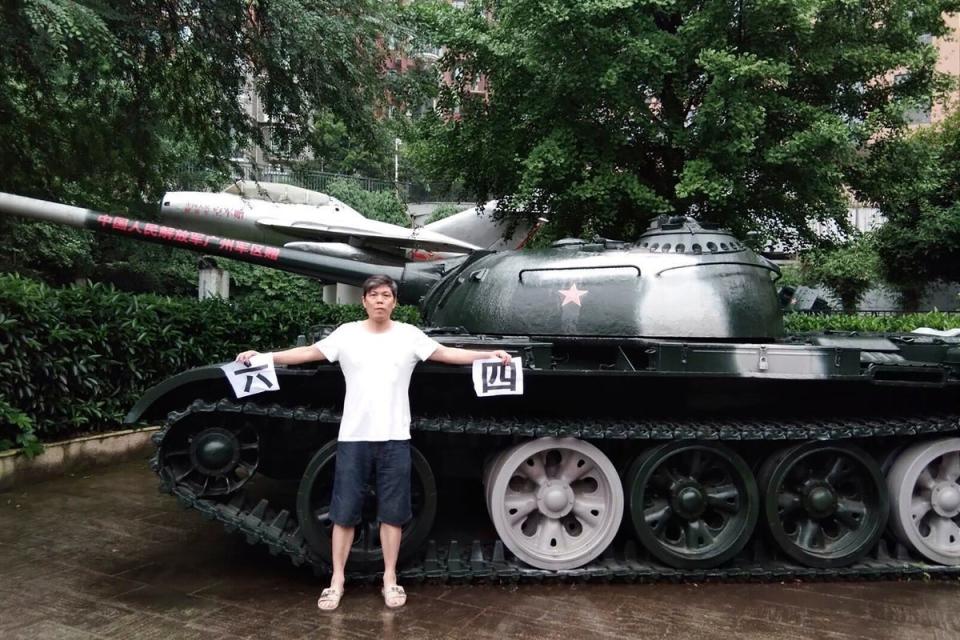 In this photo taken on 4 June 2018 by Chen Siming, he holds up pieces of paper with the Chinese characters for 6 and 4 referring to 4 June next to a display of an obsolete tank in Zhuzhou in central China’s Hunan province (AP)