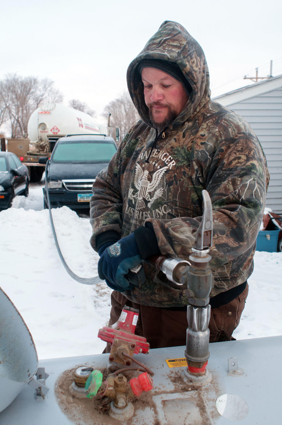 In this Thursday, Feb. 6, 2014 photo Ken Snider, who drives a propane truck, fills a tank outside a home on the Standing Rock Reservation in Fort Yates, N.D. Snider said the price of propane on the reservation this winter peaked at $4.65 a gallon, which is more than doubling of the fuel’s cost has crippled efforts to stay warm _ and alive _ through the harsh winter where most people rely on propane to heat their often ramshackle homes. (AP Photo/Kevin Cederstrom)