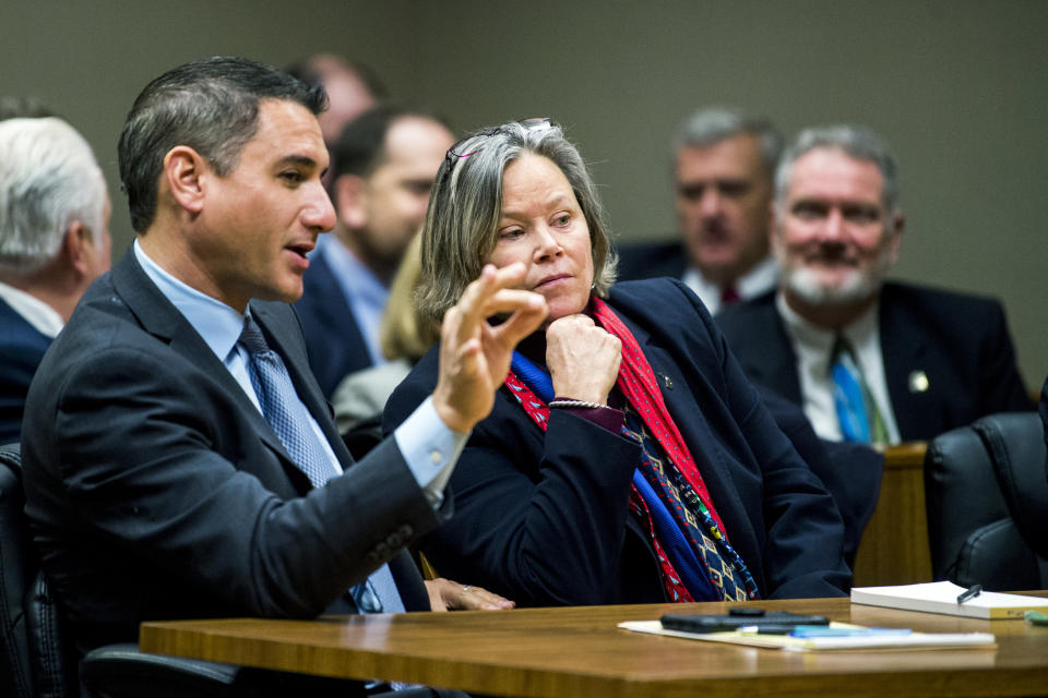 Defense attorney Steve Tramontin speaks with his client Dr. Eden Wells before a hearing Friday, Dec. 7, 2018, at Genesee District Court in downtown Flint, Mich. Wells, Michigan's chief medical executive, will stand trial on involuntary manslaughter and other charges in a criminal investigation of the Flint water crisis, a judge ruled Friday. (Jake May/The Flint Journal via AP)