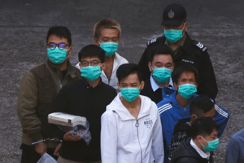 Pro-democracy activists Ivan Lam and Joshua Wong walk to a prison van to head to court, after pleading guilty to charges of organising and inciting an unauthorised assembly near the police headquarters during last year's anti-government protests