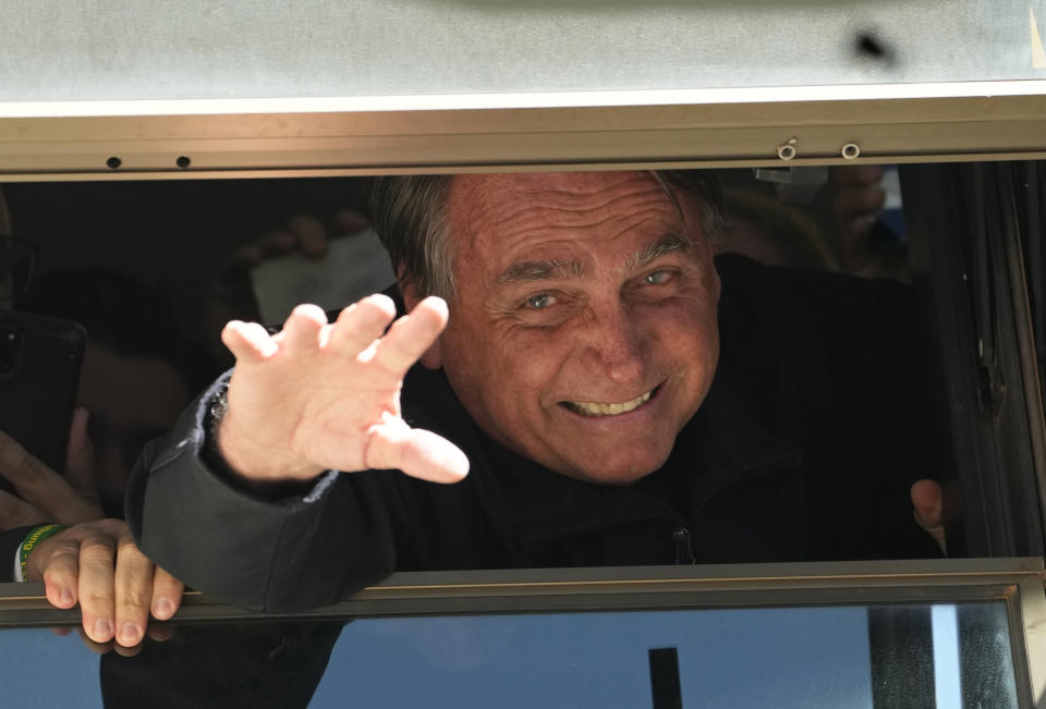 Brazil's former President Jair Bolsonaro waves to supporters at the Liberal Party's headquarters in Brasilia, Brazil, Thursday, March 30, 2023. Bolsonaro arrived back in Brazil on Thursday after a three-month stay in Florida, seeking a new role on the political scene. (AP Photo/Eraldo Peres)