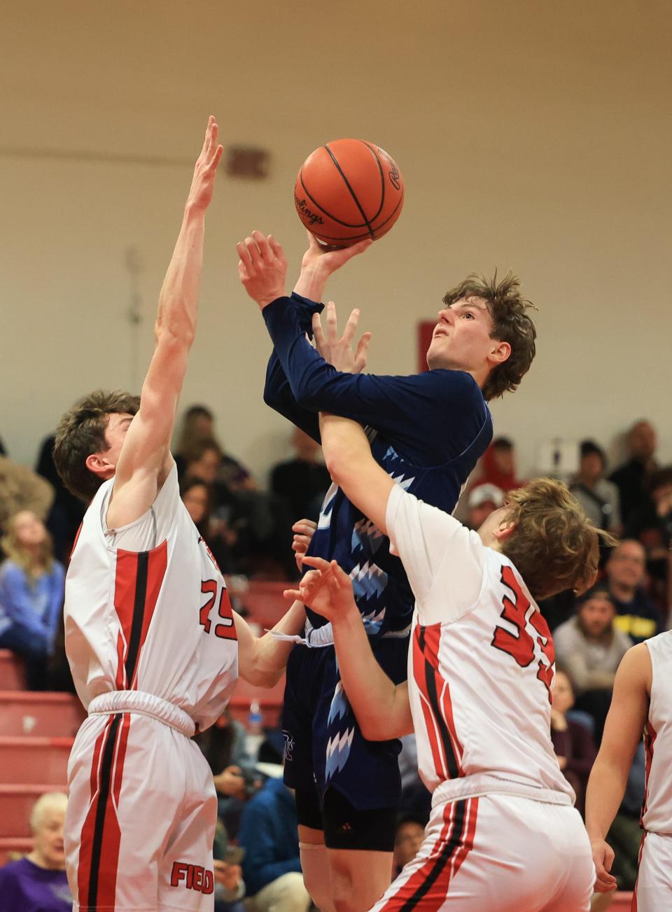 Rootstown senior Nick Wancik leaps up over Field seniors Cole Muncy and Xander Rorrer during Tuesday night’s game at Field High School. Field defeated Rootstown 61-50.