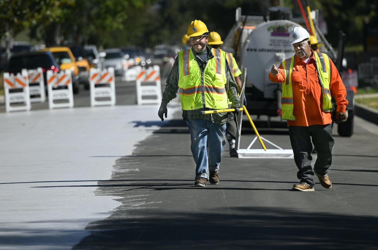 A road crew paints a street in Los Angeles with coating designed to reduce heat. <a href="https://www.gettyimages.com/detail/news-photo/jordan-avenue-north-of-hart-street-is-getting-a-new-surface-news-photo/1166648116" rel="nofollow noopener" target="_blank" data-ylk="slk:John McCoy/MediaNews Group/Los Angeles Daily News via Getty Images;elm:context_link;itc:0;sec:content-canvas" class="link ">John McCoy/MediaNews Group/Los Angeles Daily News via Getty Images</a>