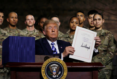 U.S. President Donald Trump holds up the National Defense Authorization Act after signing it in front of soldiers from the U.S. Army's 10th Mountain Division at Fort Drum, New York, U.S., August 13, 2018. REUTERS/Carlos Barria